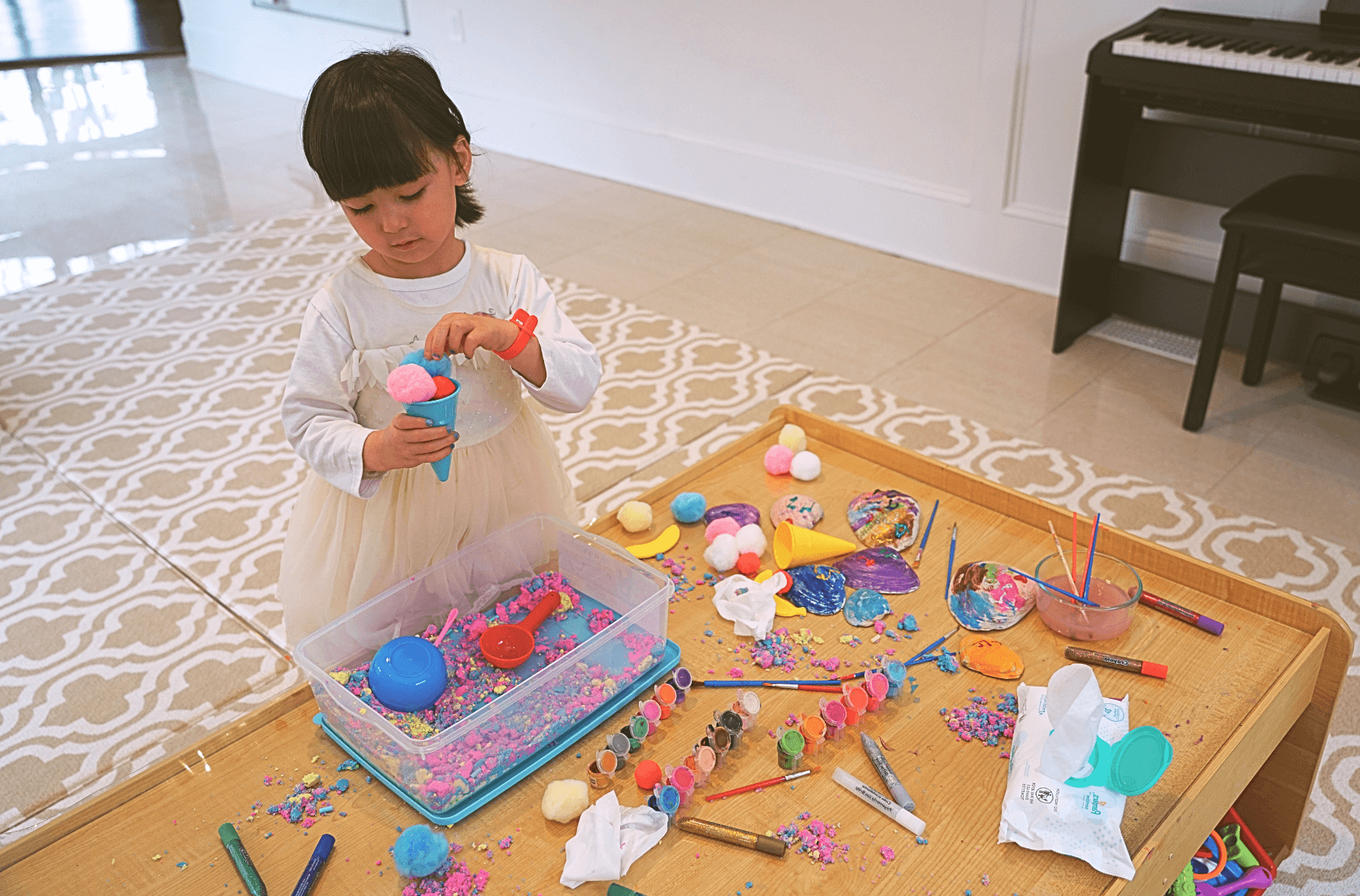 Little child doing arts and crafts in the playroom on a messy table